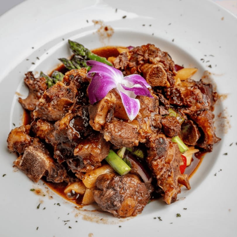 Taste of the Caribbean's oxtail dish, garnished with a purple orchid, asparagus, and plantains.