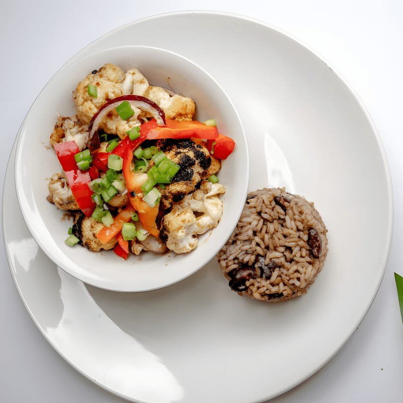 Roasted cauliflower with red peppers, onions, and scallions, served with rice and beans.